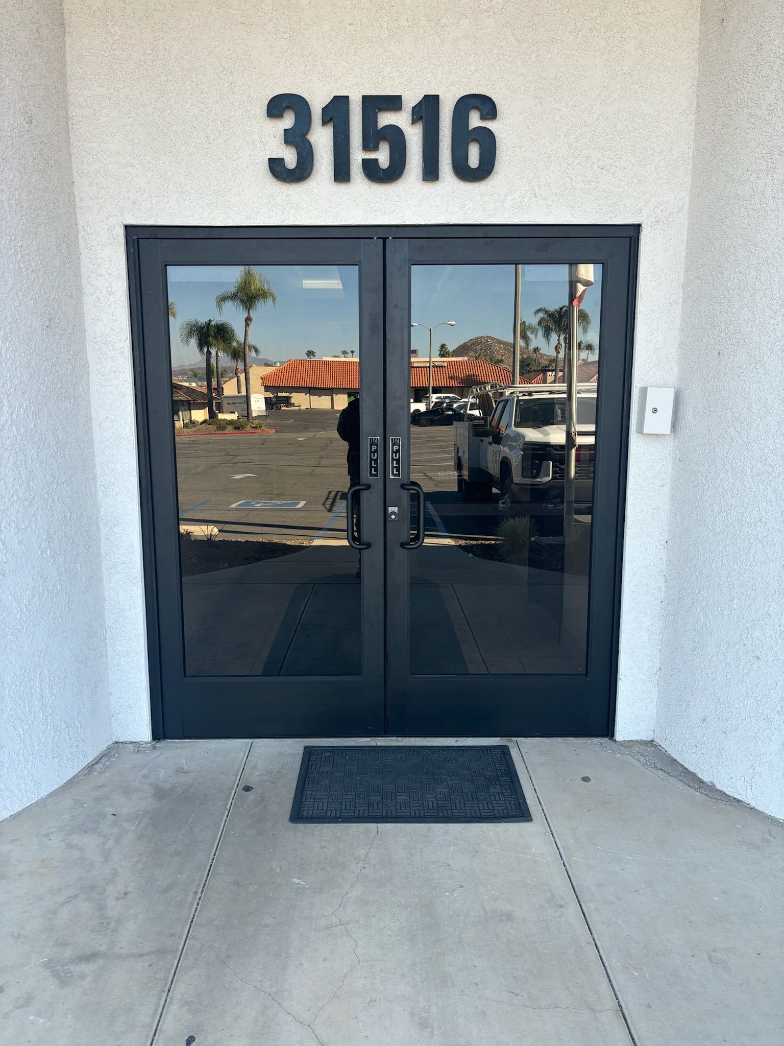 Black double doors with reflective glass, address number 