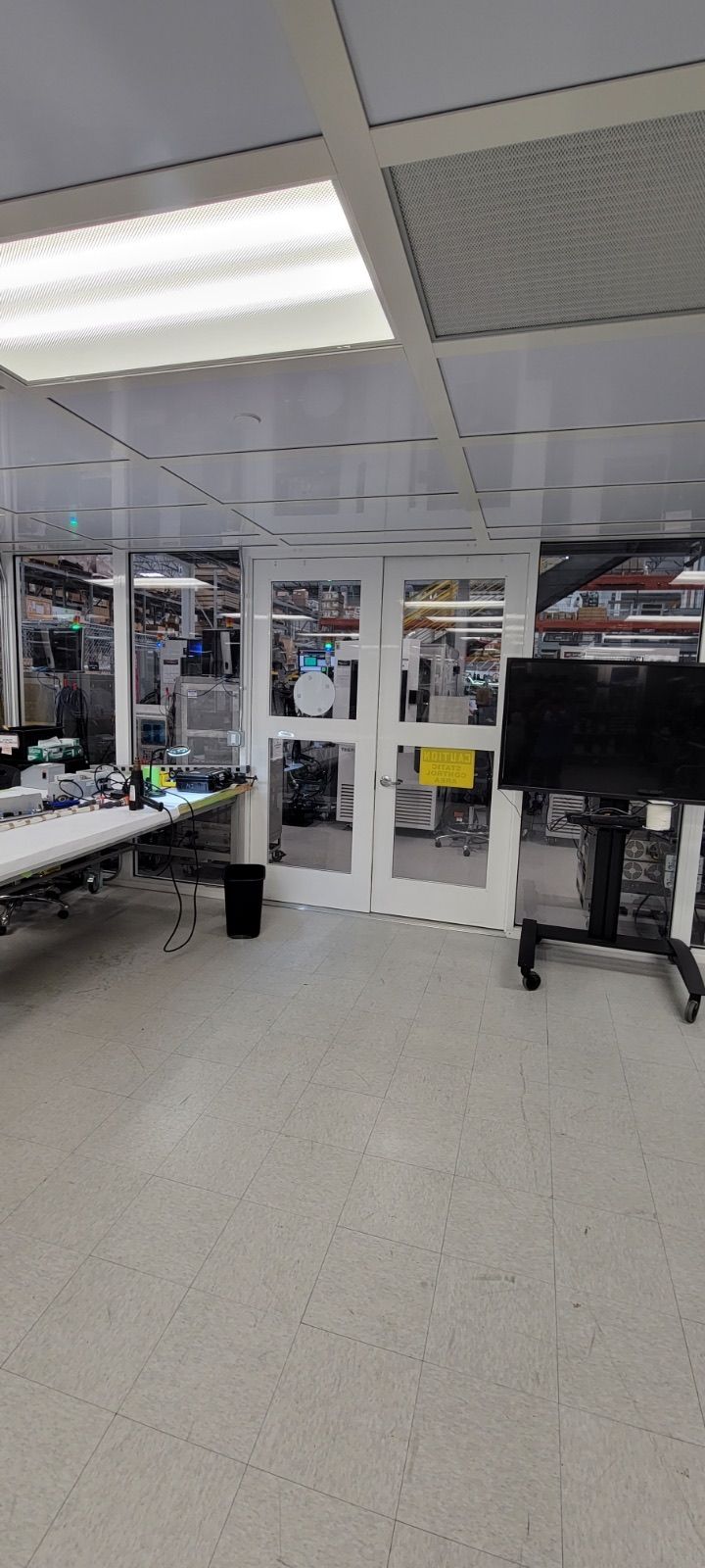 A white office space with a closed double door and a black television.
