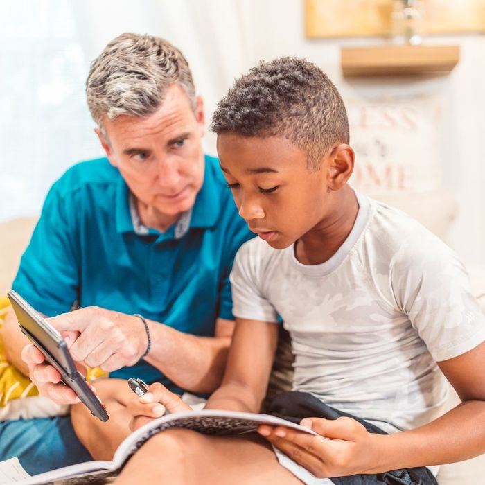 A man is teaching a young boy how to use a tablet computer.