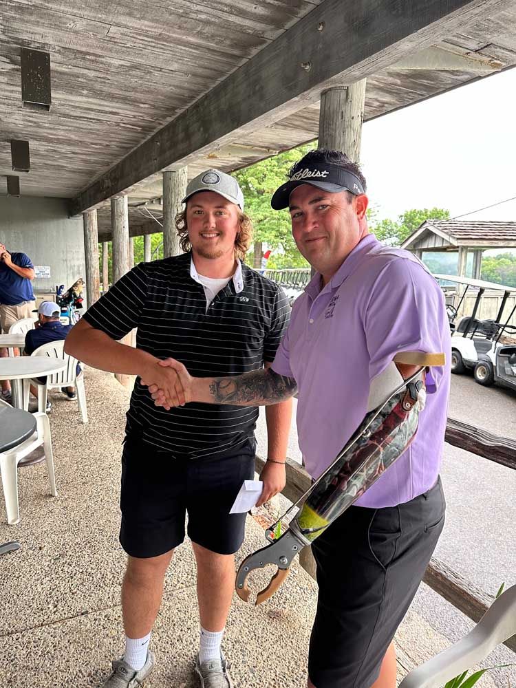 A man with a prosthetic arm is shaking hands with another man.