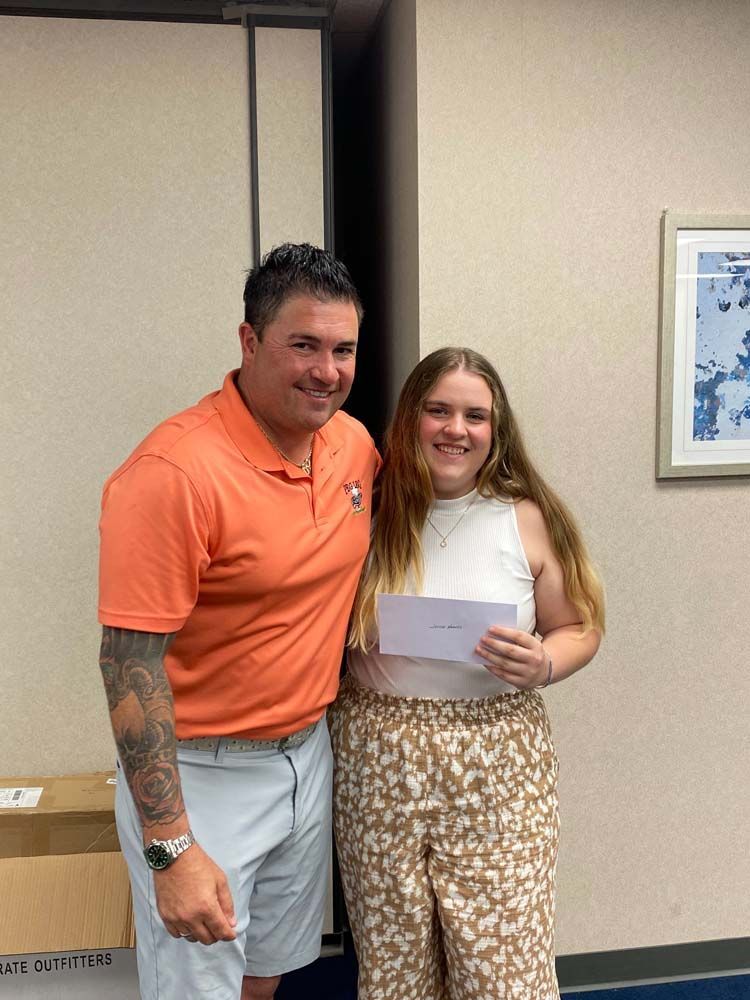 A man and a woman are standing next to each other in a room . the woman is holding a check.