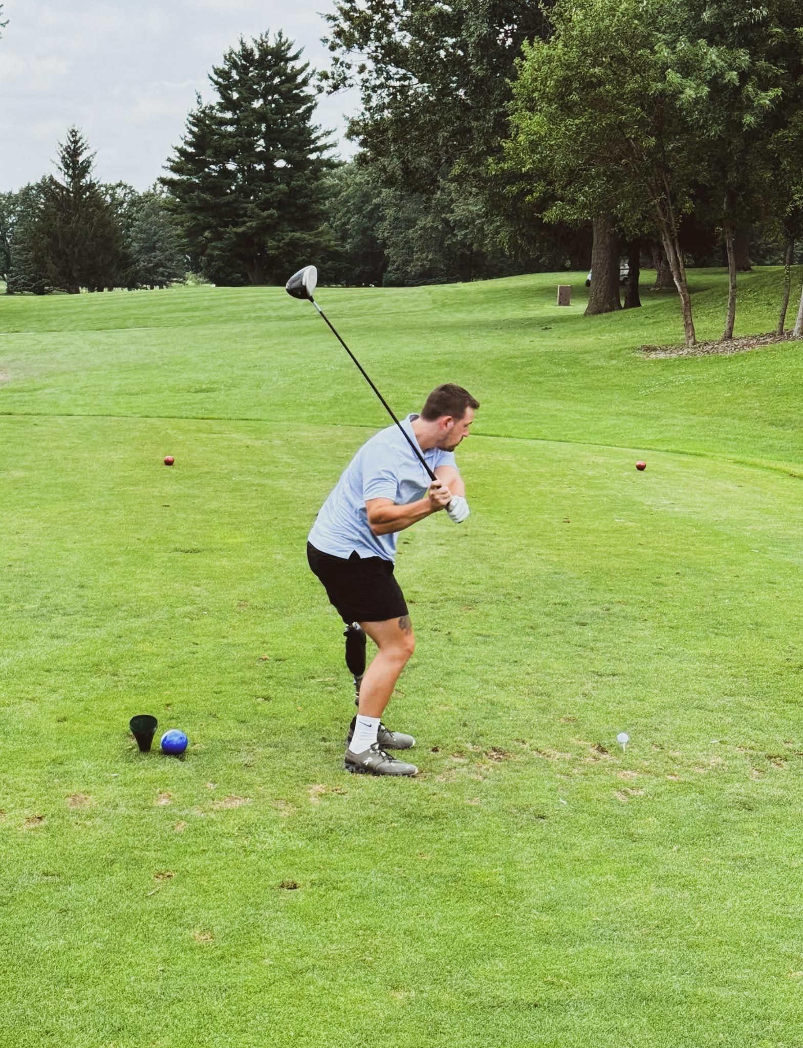 A man is swinging a golf club on a golf course.