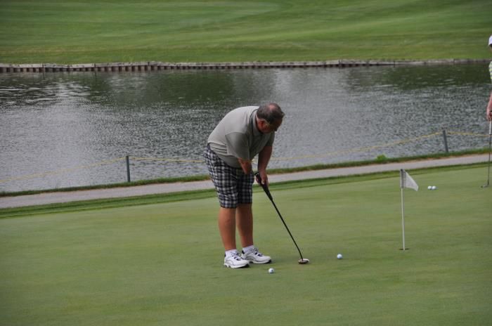 A man is putting a golf ball on a golf course.