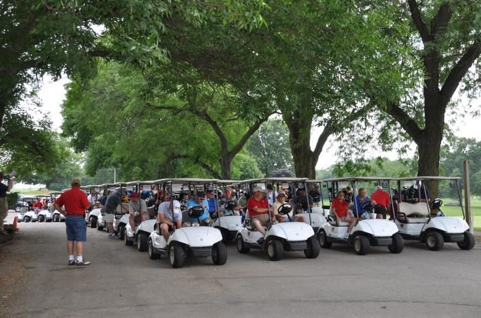 A row of golf carts are parked in a parking lot