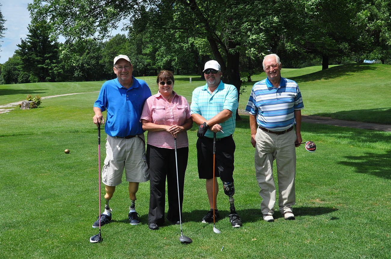 A group of people standing on a golf course holding golf clubs.