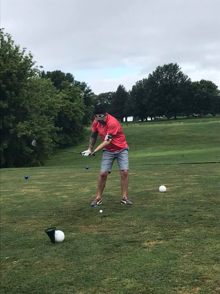 A man is swinging a golf club at a golf ball on a golf course.