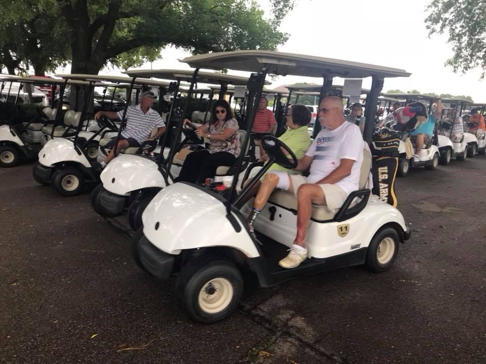 A group of people are riding golf carts in a parking lot