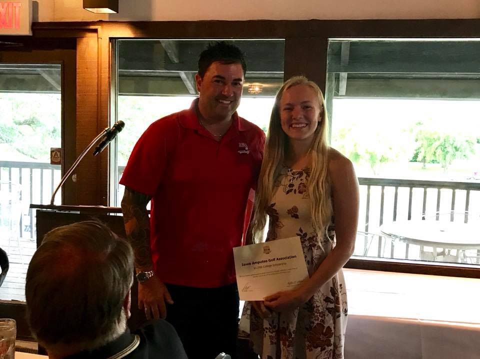 A man and a woman are standing next to each other in a room holding a certificate.