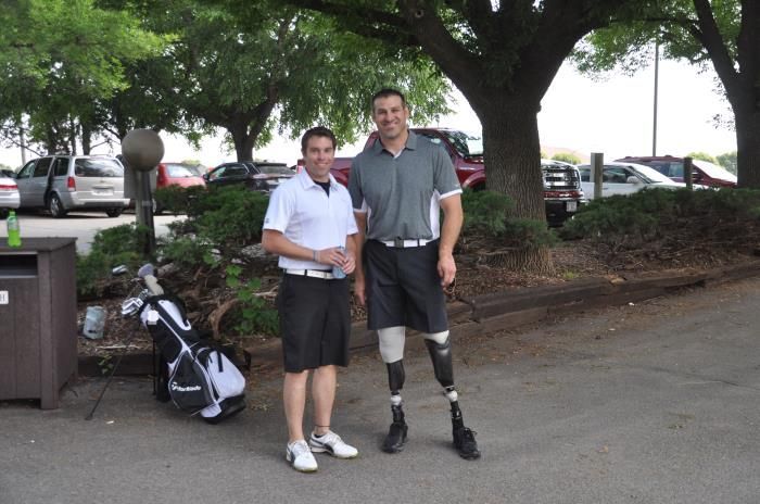 A man with a prosthetic leg stands next to another man