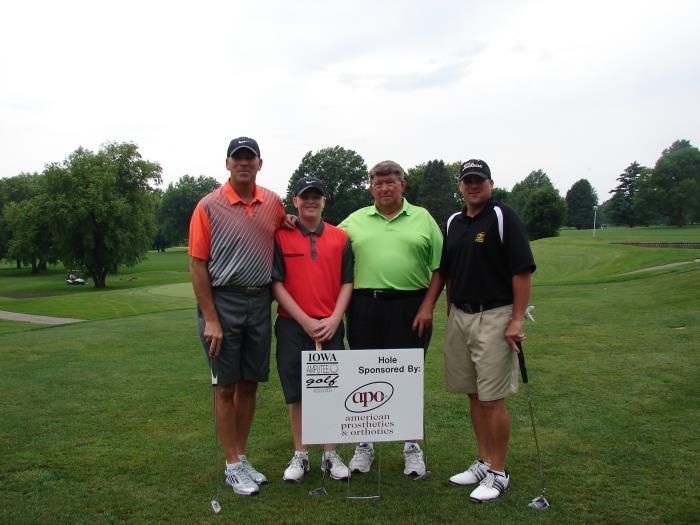 Four men are posing for a picture on a golf course