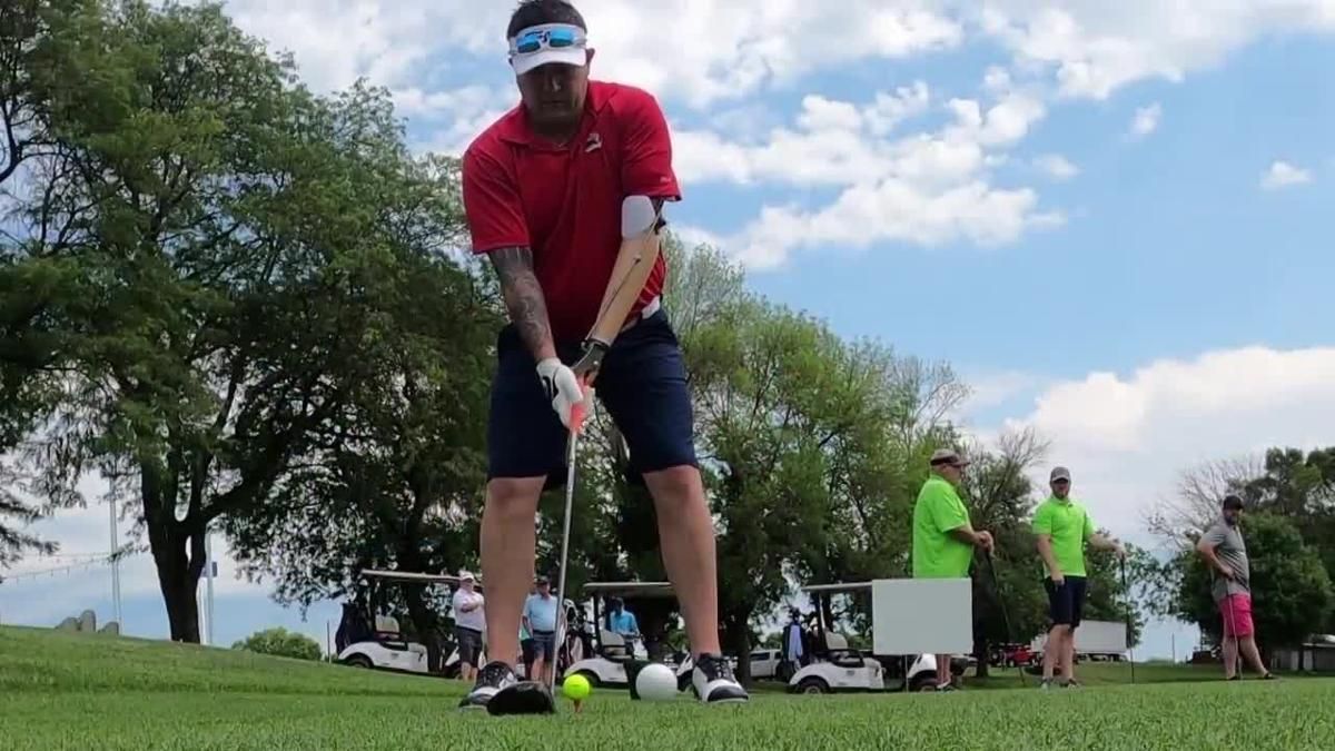 A man is swinging a golf club on a golf course.