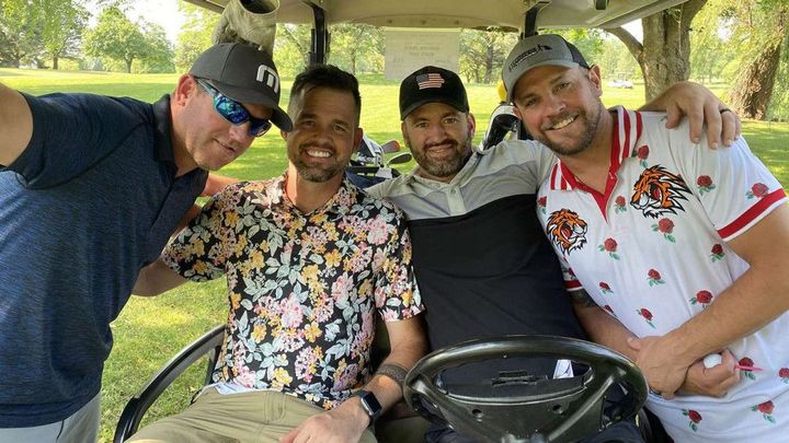 A group of men are posing for a picture in a golf cart.