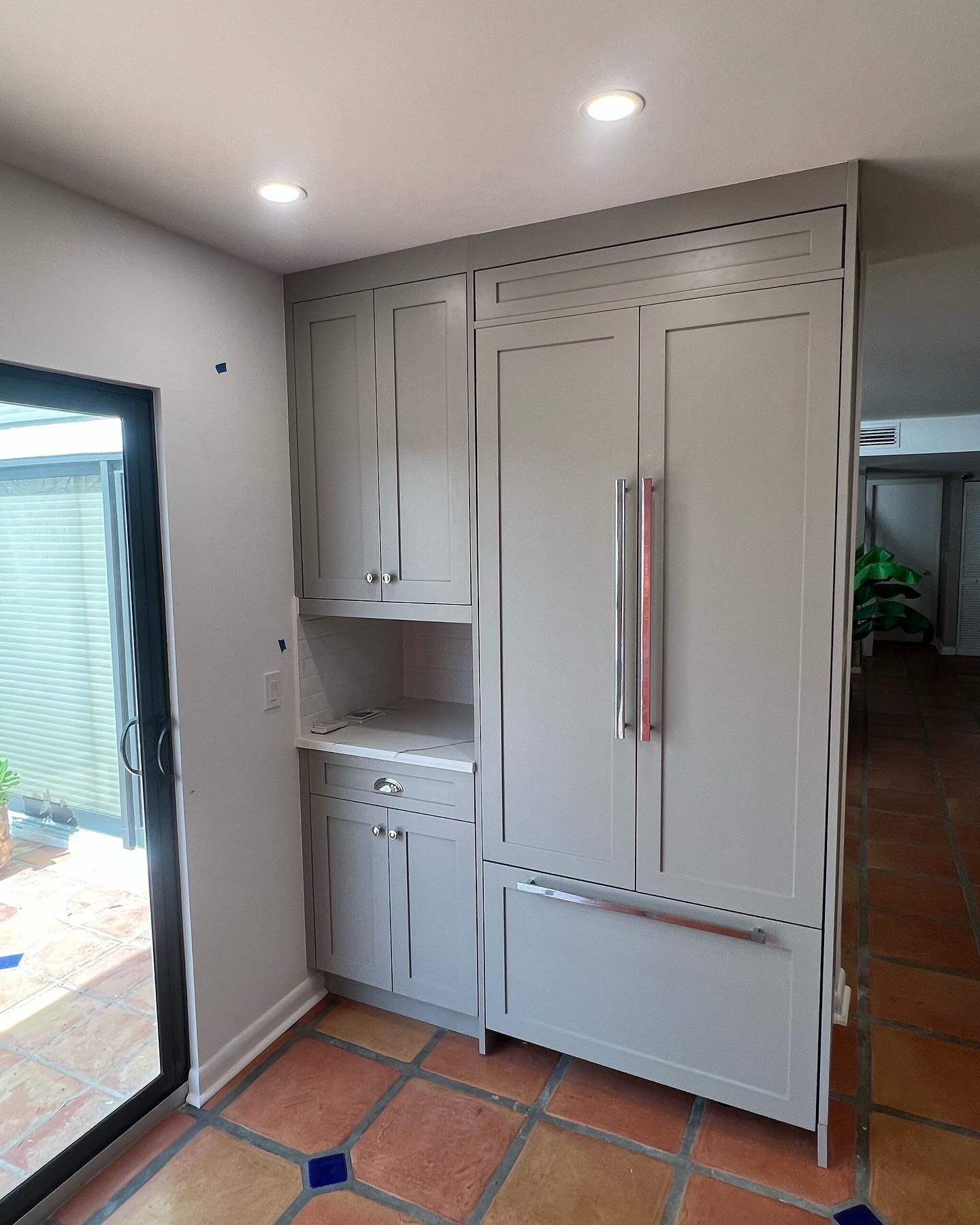 A kitchen with white cabinets and a sliding glass door.