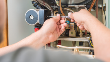 Hands using a screwdriver to repair wiring inside an electrical control panel