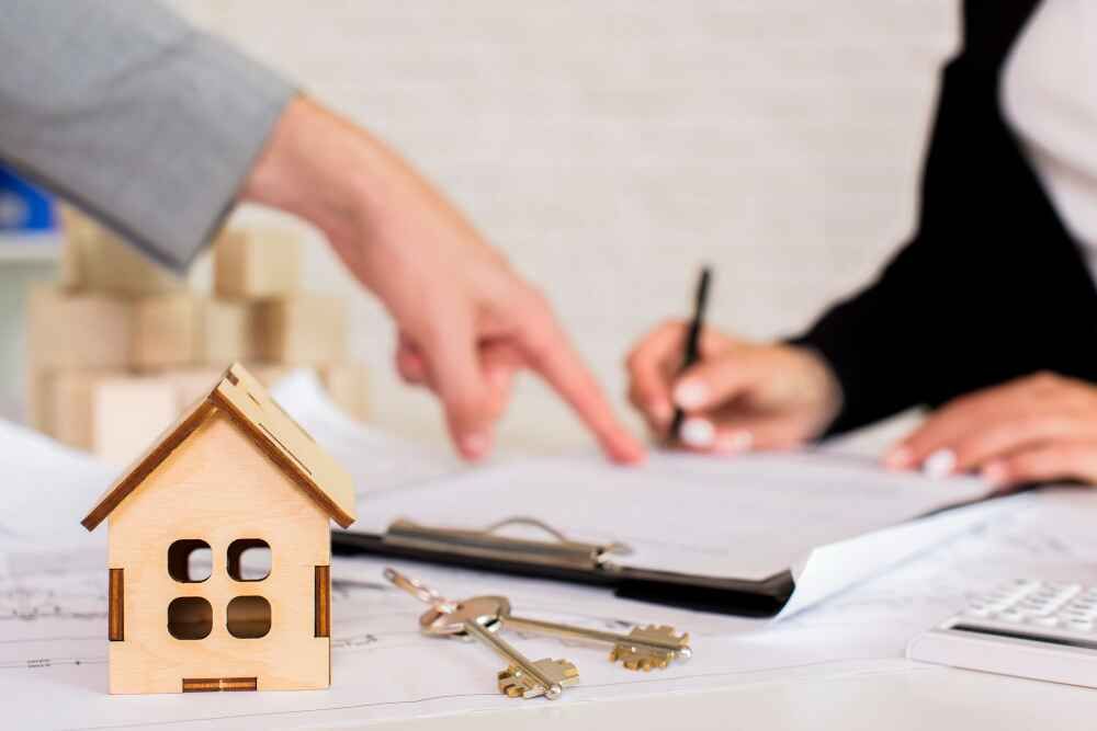 Wooden house model with keys symbolizing property management and rental fraud prevention.