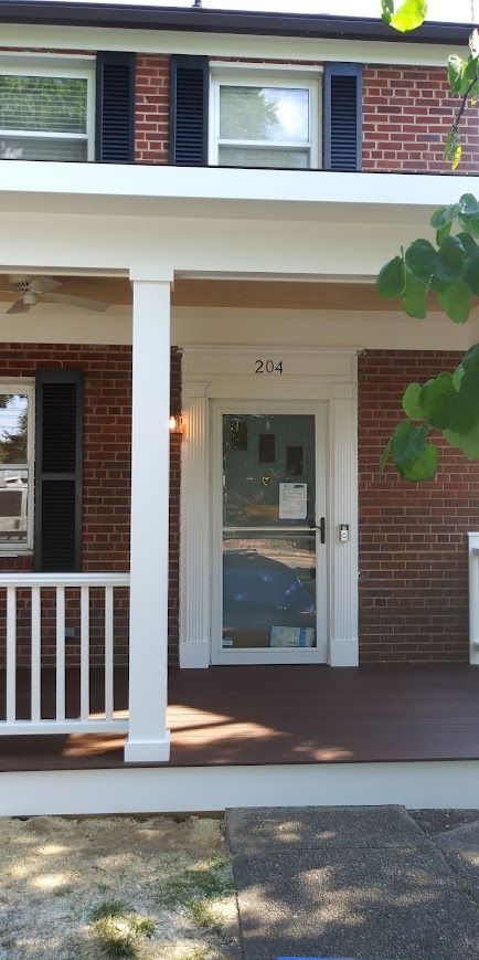 A brick building with a porch, a glass door with the number 204 above it.