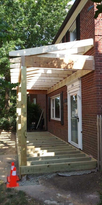 Construction of a wooden porch, attached to a brick building.