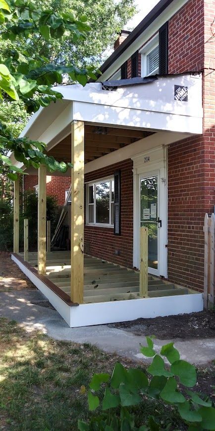 Newly constructed porch with wooden posts and deck on a brick building.