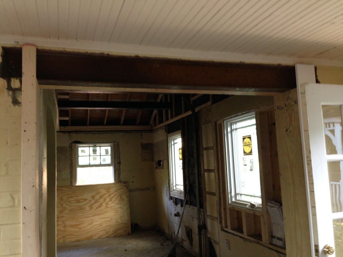 Interior of a room under construction with a visible wooden beam across an opening.