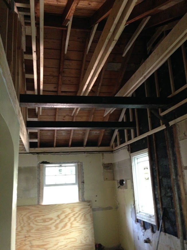 Interior view of a room under construction, with exposed beams and framing.