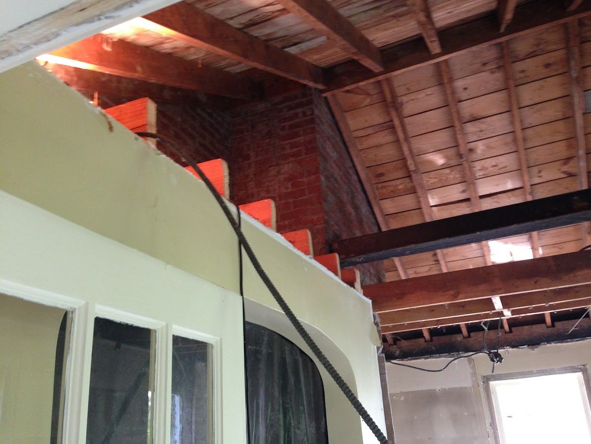 Interior renovation: exposed brick and wooden beams under a slanted ceiling.