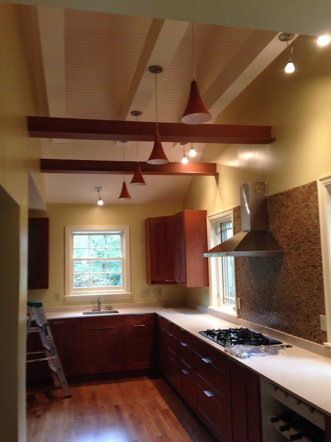 Kitchen with brown cabinets, white countertop, wood floor, and pendant lights.