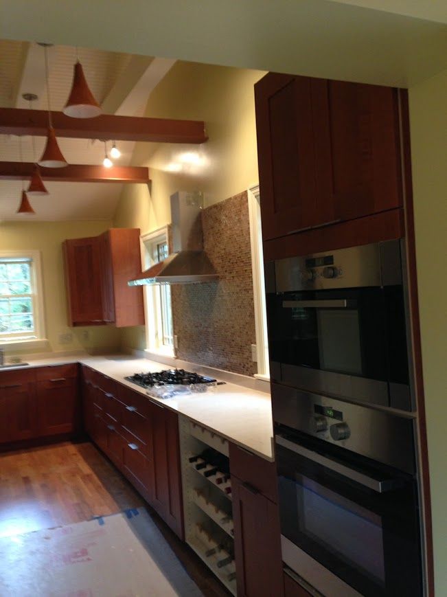 Modern kitchen with dark wood cabinets, stainless steel appliances, and beige walls.