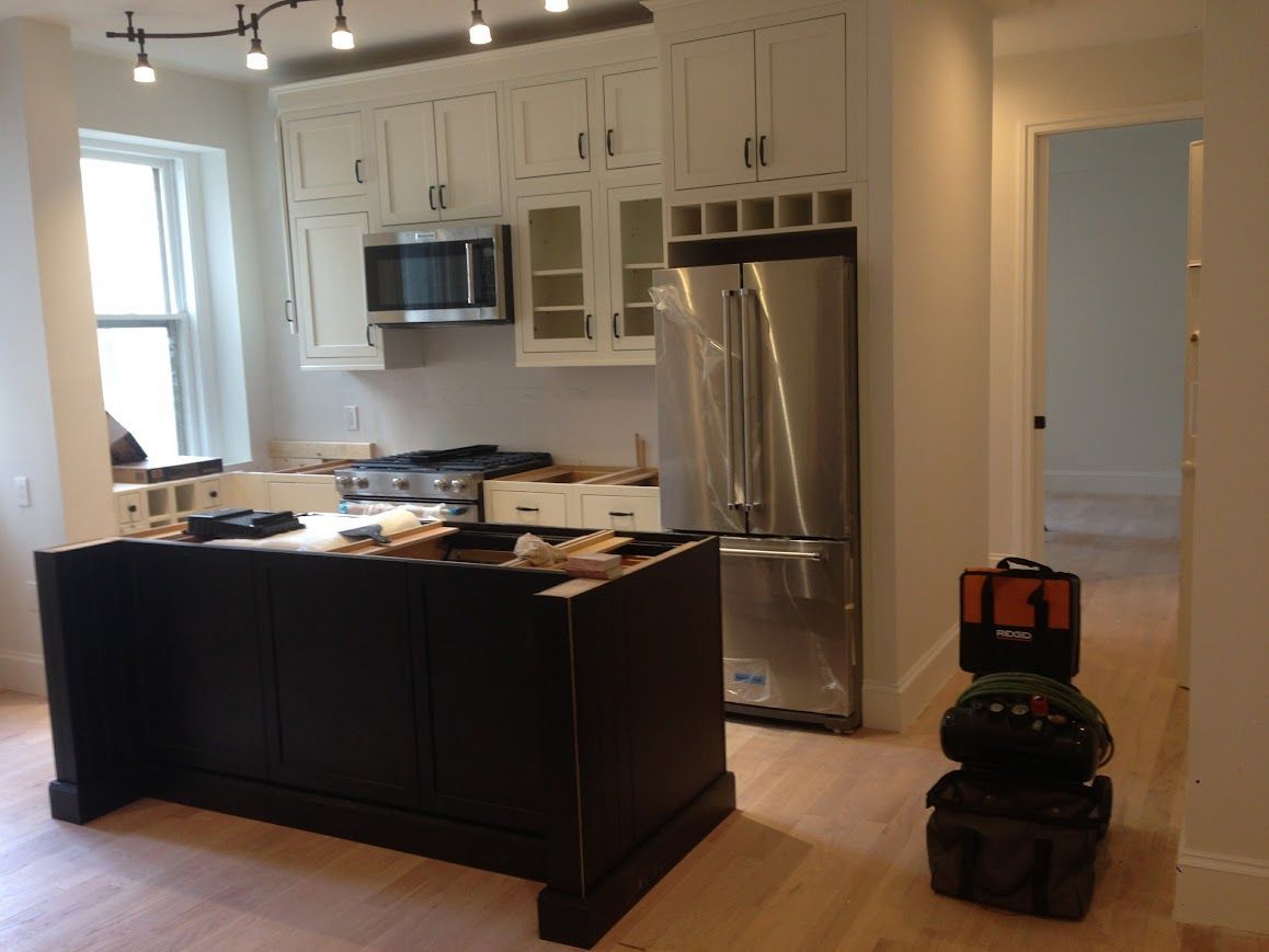 Kitchen with white cabinets, stainless steel appliances, dark island, and tools.