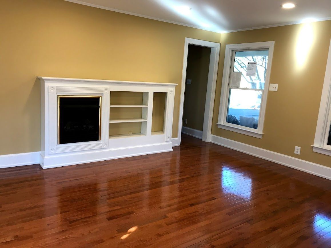 Wooden floor, yellow walls, and white trim living room with built-in cabinet and window.