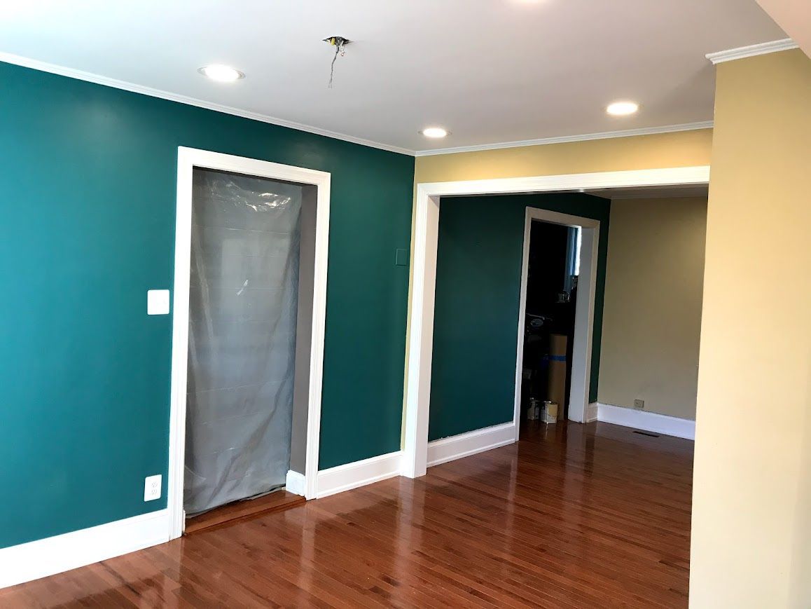 A room with teal and tan walls, white trim, and a hardwood floor.