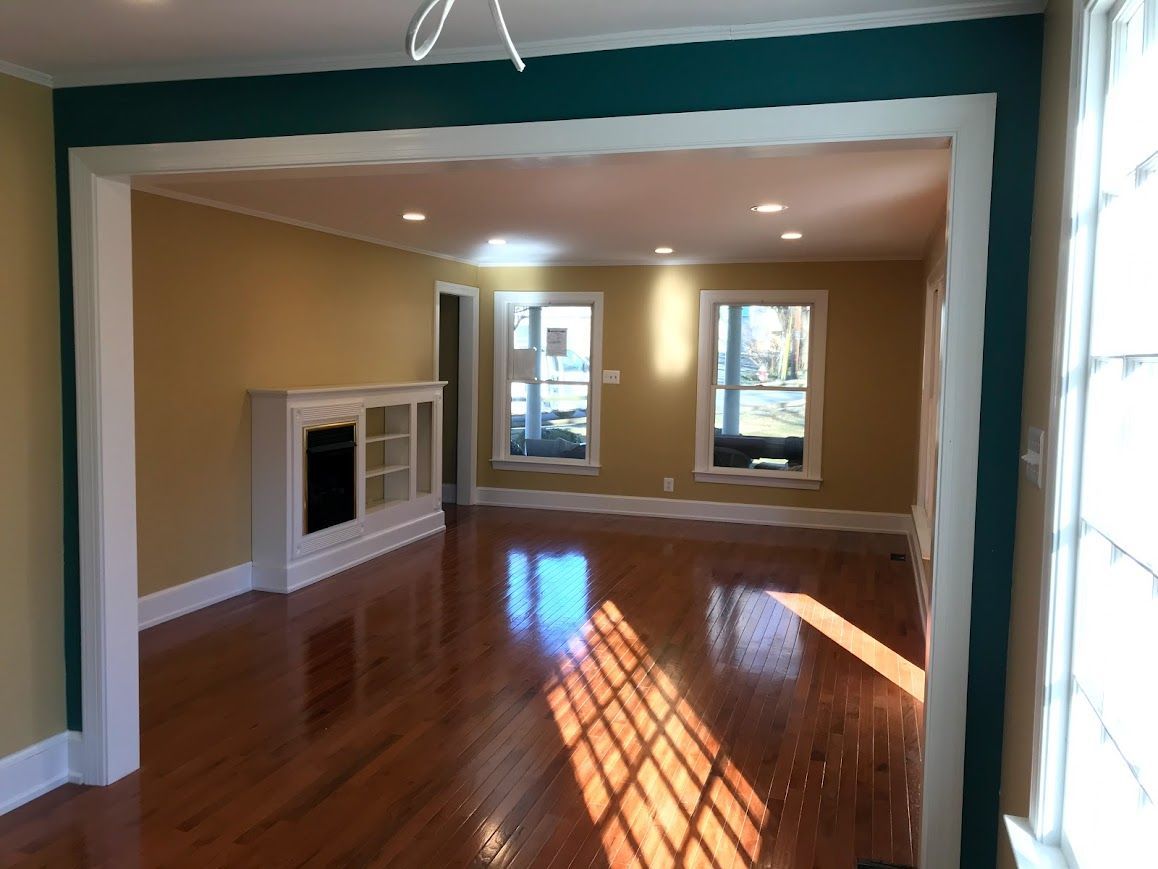 Bright interior shot of a room with wood floors, yellow walls, and teal trim around the entryway.