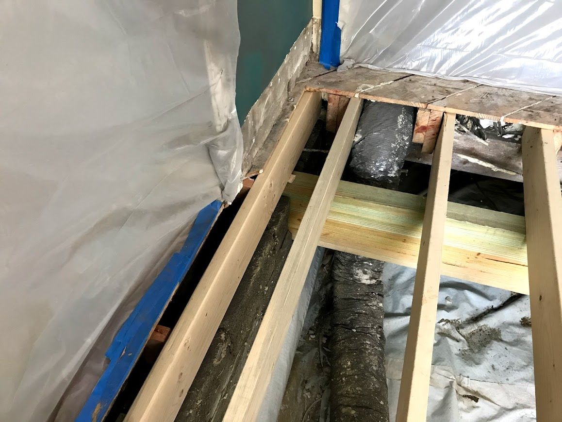 Framed wood construction with insulation, ductwork, and plastic sheeting.