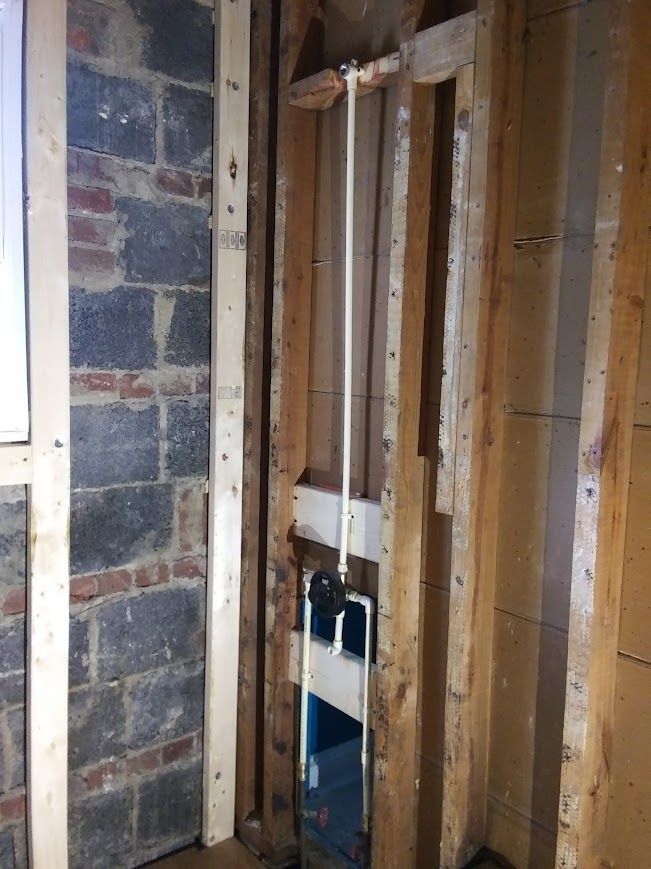 Wall studs, plumbing, and brick wall in a construction setting.