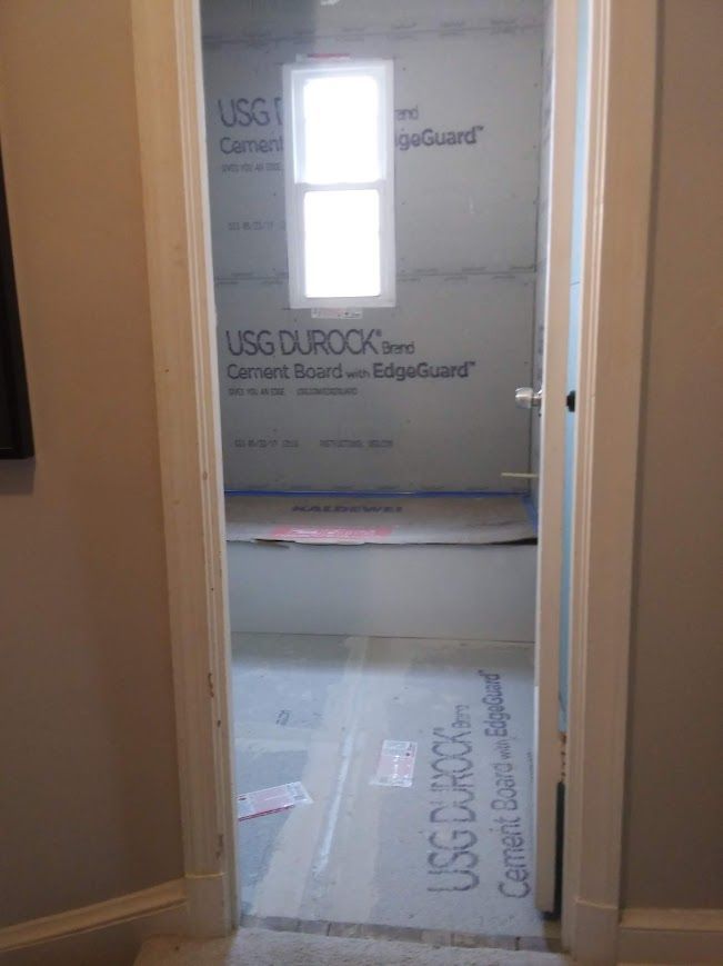 Bathroom doorway, unfinished with cement board walls and small window.