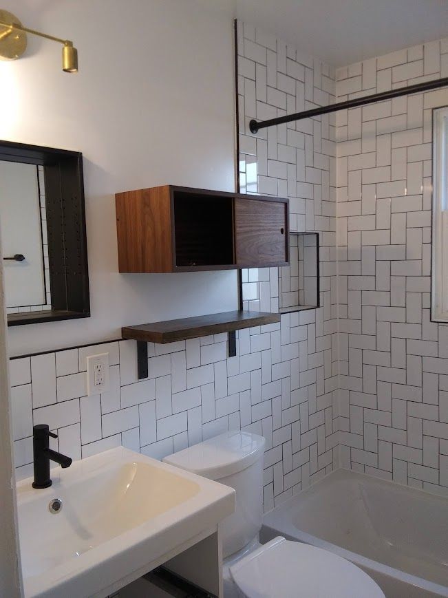 Modern bathroom with white subway tile, a wooden cabinet, and black fixtures.