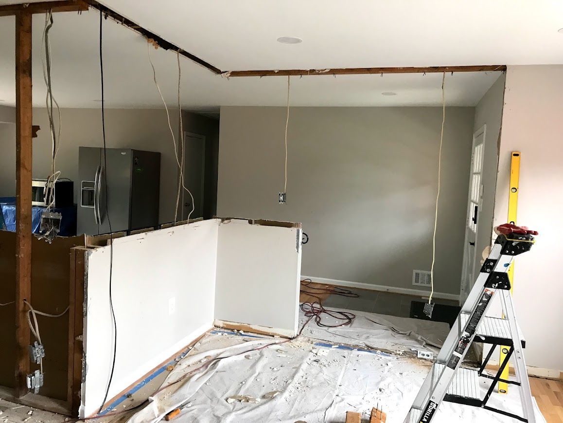 Interior wall demolition; wires hang from ceiling, debris on floor.