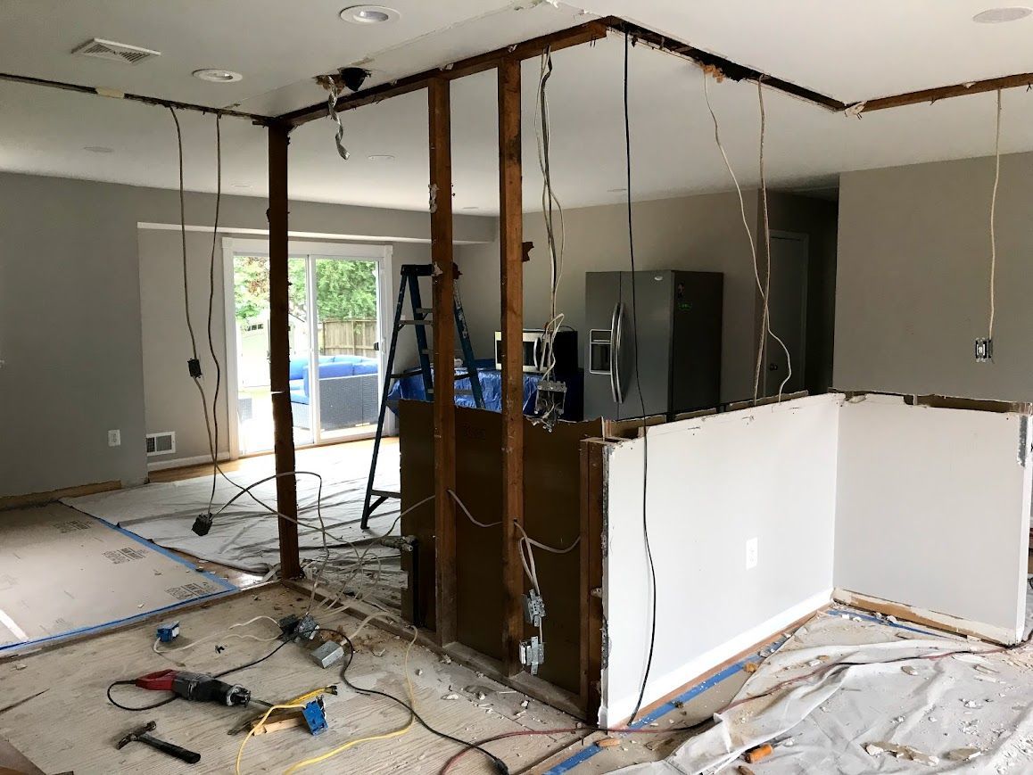 Kitchen renovation in progress, walls and ceiling partially removed, wires exposed.