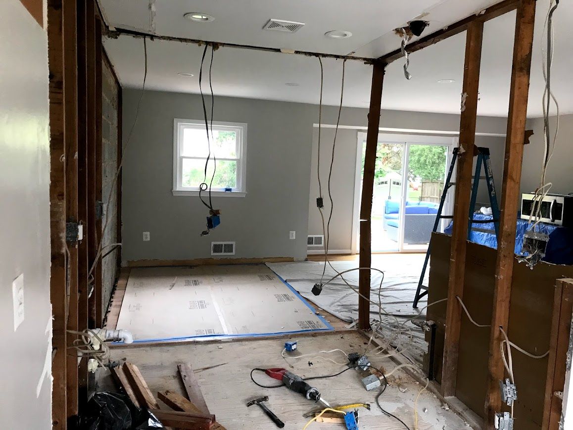 Interior room under construction, exposed studs, wiring hanging. Tools on the floor.