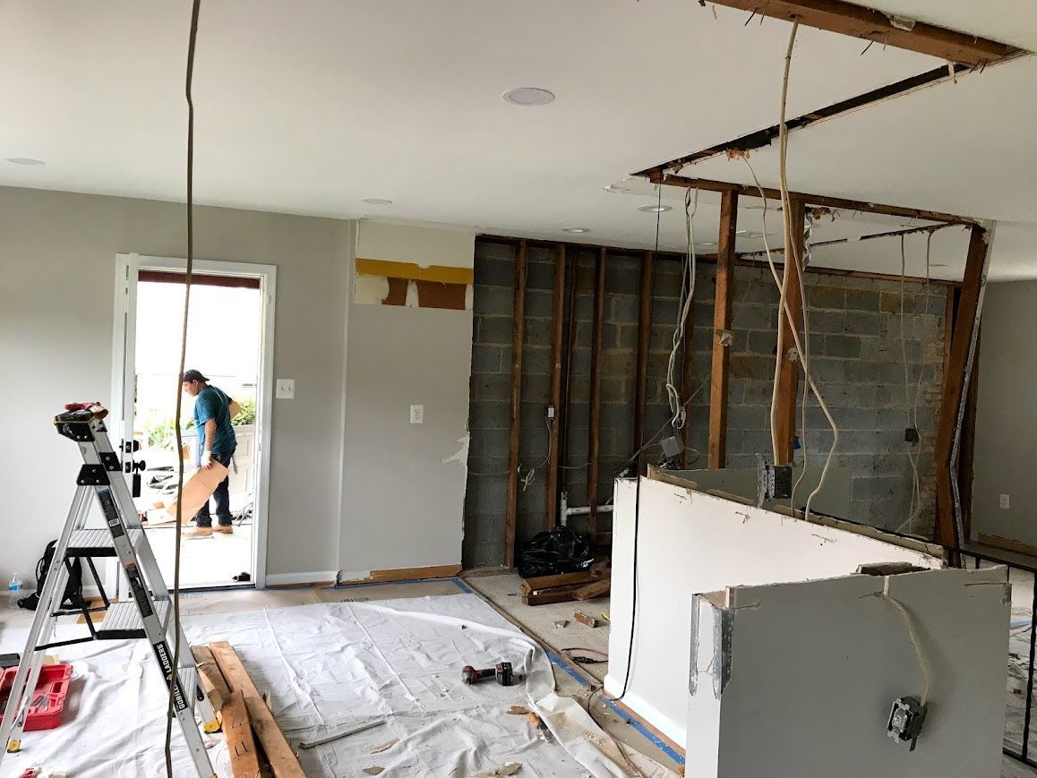Interior undergoing renovation; exposed wall studs, concrete blocks, drywall, and a person in doorway.
