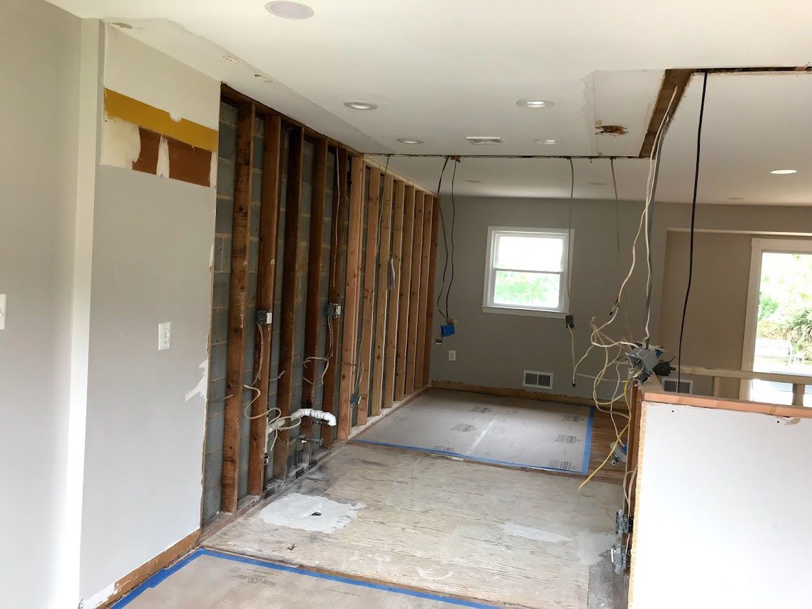 Interior renovation: Exposed wall studs, electrical wires, and plumbing visible. Room is gutted.