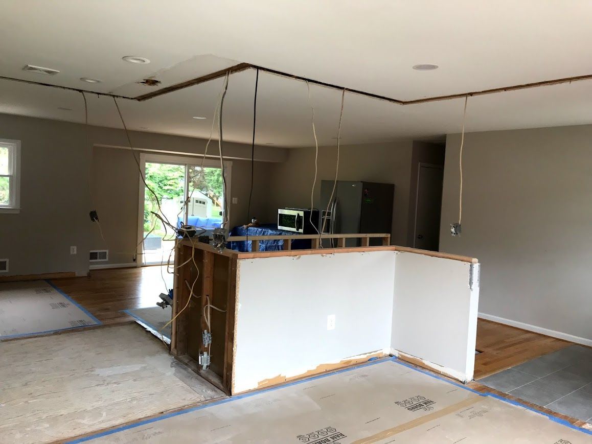 Kitchen under renovation; partial island with exposed framing, exposed wiring, and bare walls.