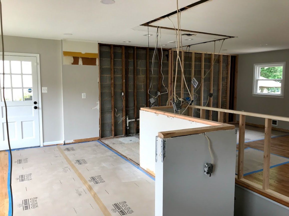 Interior during renovation with exposed wall studs, electrical wires, and partial drywall.