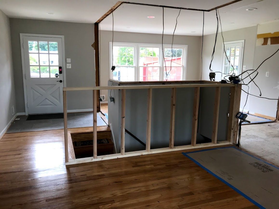 Interior view of a home renovation in progress with exposed framing, staircase, and wiring.