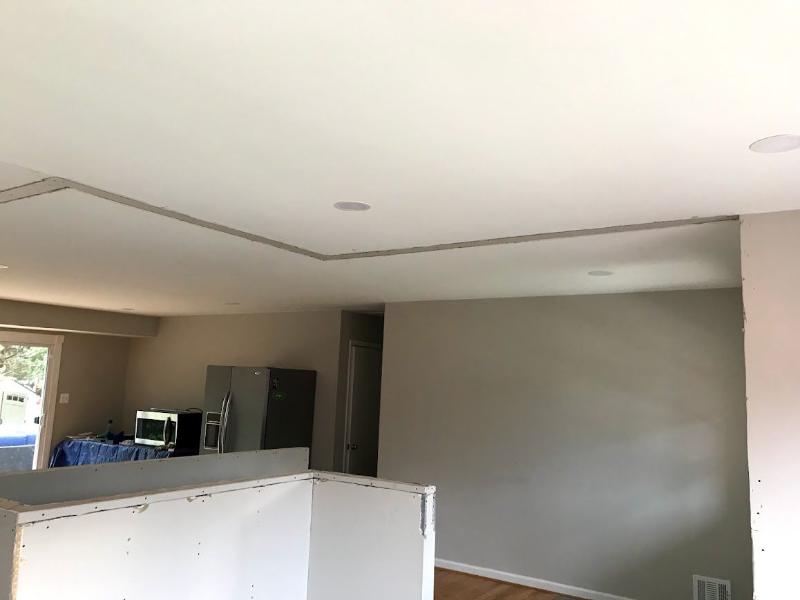 Interior view of a room with a light-colored ceiling and walls; Recessed lighting, a doorway, and a partial wall are visible.