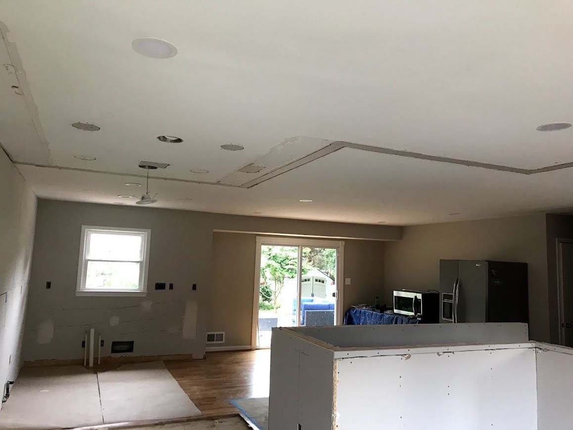 Interior of a room under construction with a kitchen island, recessed lighting, and a sliding glass door.