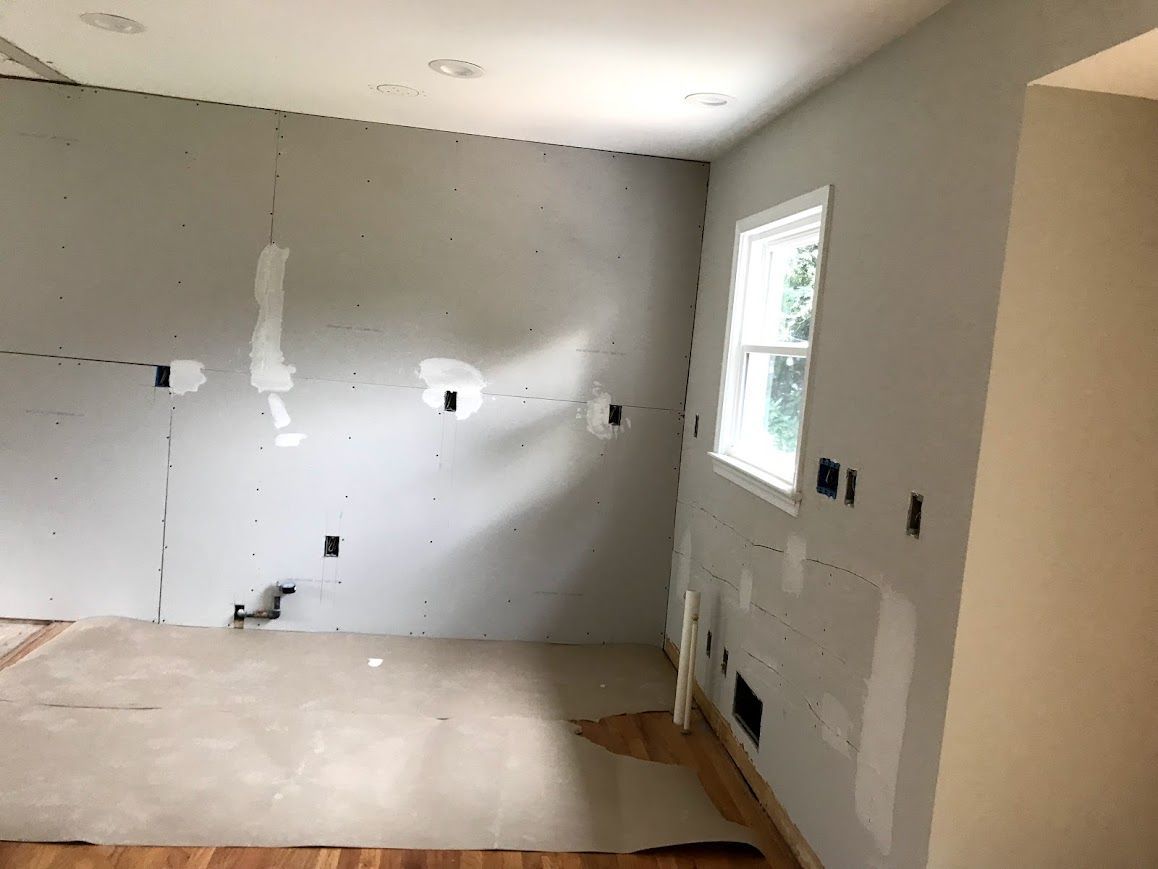 Interior room renovation with unfinished walls, electrical outlets, and a window.