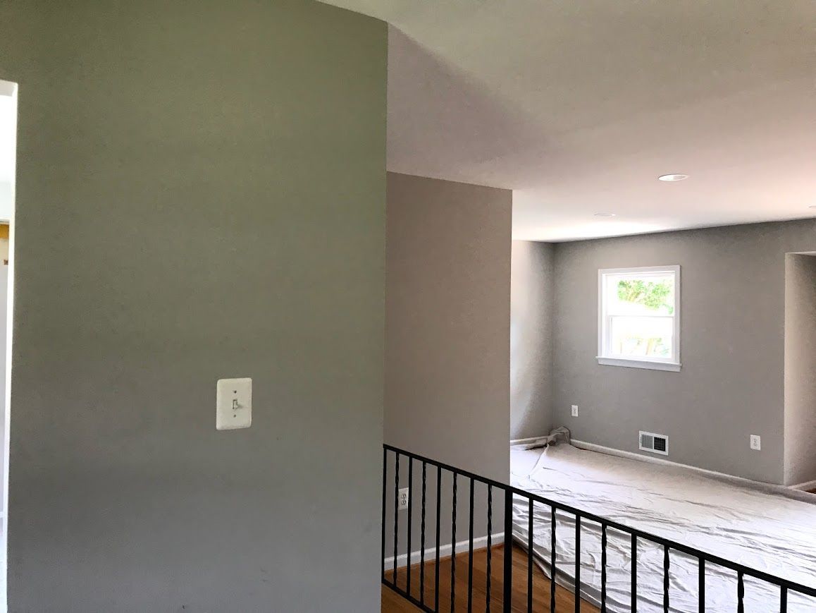 Interior view of a room with gray painted walls, a window, and a black railing.