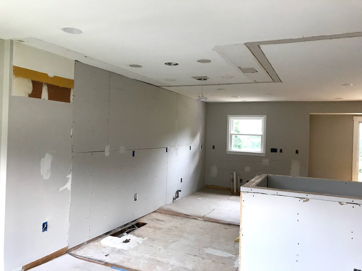 Interior of a kitchen under renovation, with drywall on walls and ceiling.