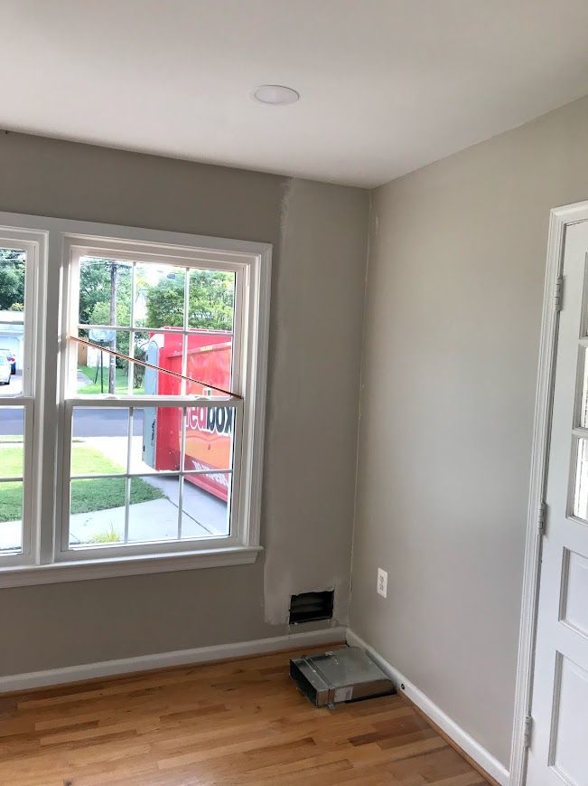 Room interior with window, door, and wooden floor. Gray walls, white trim. Empty space.