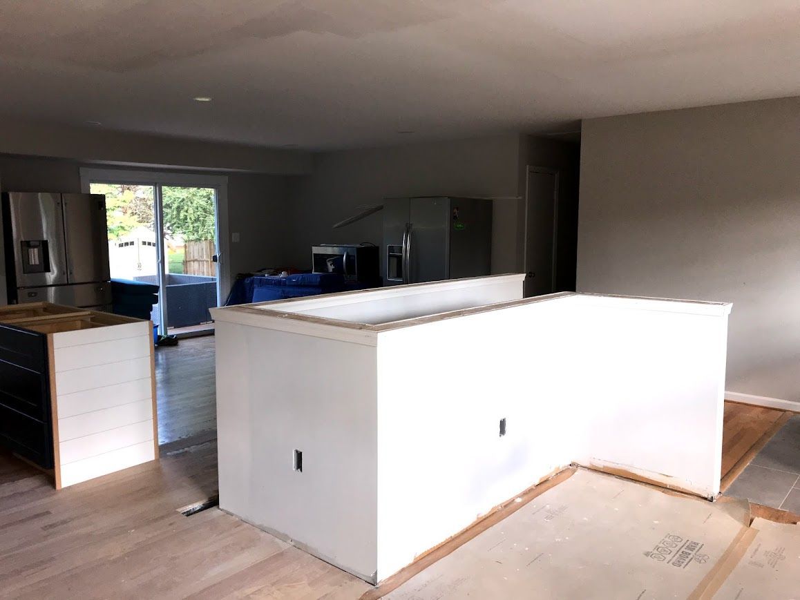 Kitchen renovation in progress: white island, cabinets, and sliding glass door to backyard.